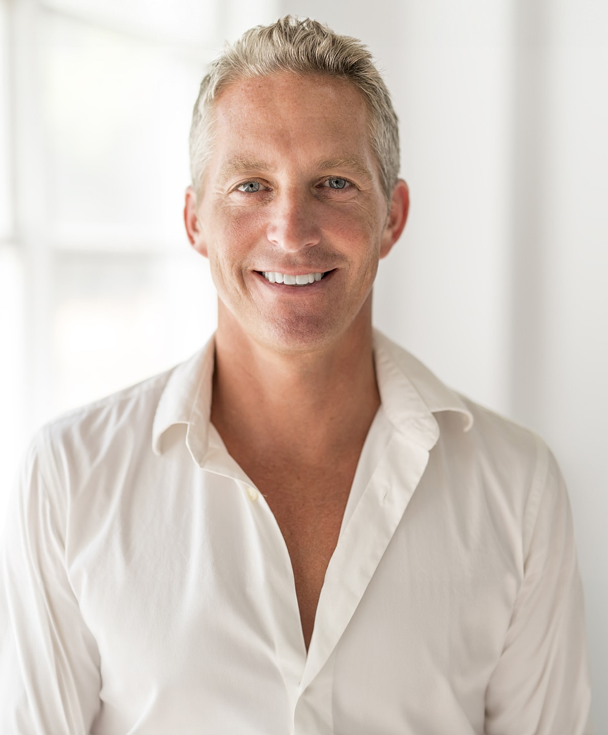 Smiling man in a white shirt, natural light.